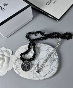 Chanel necklace on marble with flower and boxes.