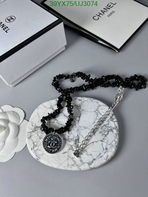 Chanel necklace on marble with flower and boxes.