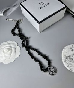 Chanel necklace with packaging on gray background.