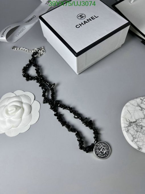 Chanel necklace with packaging on gray background.