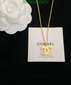 Gold pendant necklace on display with white flower.