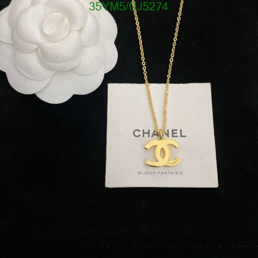 Gold pendant necklace on display with white flower.