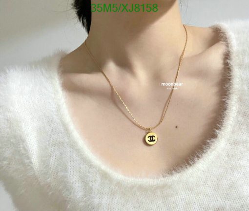 Person wearing a designer pendant necklace.