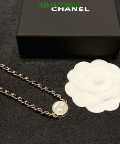 Chanel necklace and white flower beside black box.