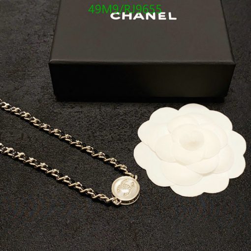 Chanel necklace and white flower beside black box.