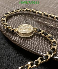 Gold bracelet with charm on textured fabric.