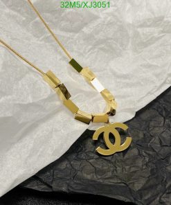 Gold designer logo pendant necklace on tissue paper.