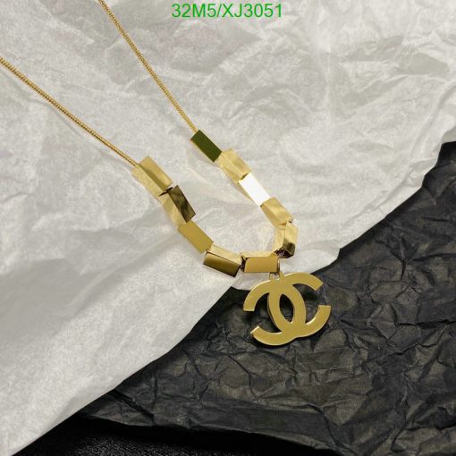 Gold designer logo pendant necklace on tissue paper.