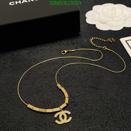 Gold designer logo necklace on dark background.