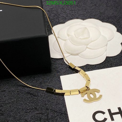 Gold designer logo necklace on display with box.