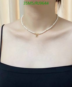 Person wearing pearl necklace with pendant.