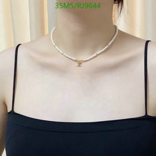 Person wearing pearl necklace with pendant.