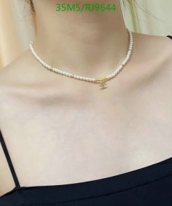 Pearl necklace with gold pendant on woman's neck.