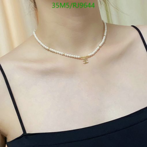 Pearl necklace with gold pendant on woman's neck.