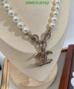 Pearl necklace with sparkling pendant on display stand.