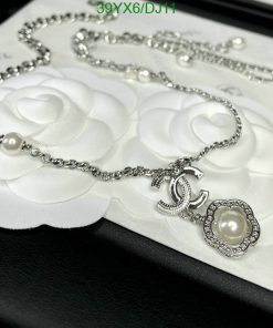 Chanel pearl necklace on white flower embossed backdrop.