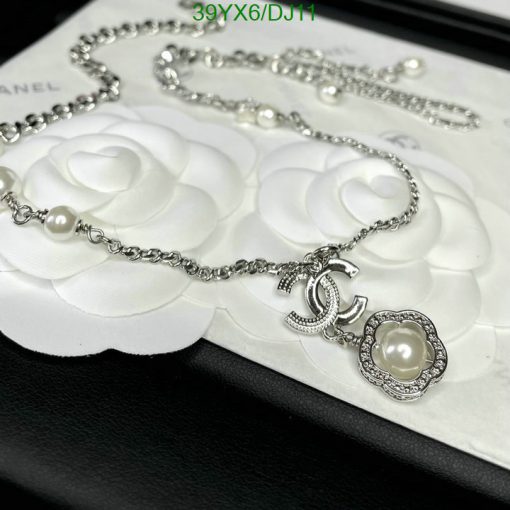 Chanel pearl necklace on white flower embossed backdrop.