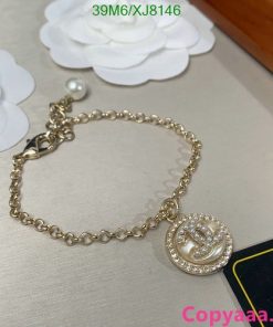 Gold chain bracelet with pendant and pearl detail.