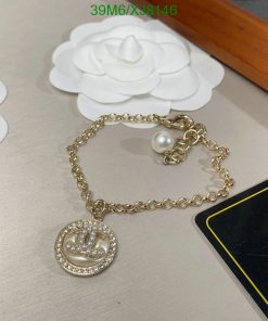 Gold bracelet with pearl and pendant on table.