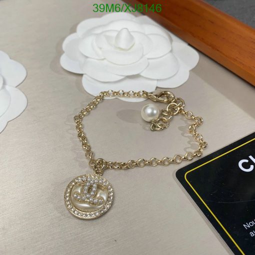 Gold bracelet with pearl and pendant on table.