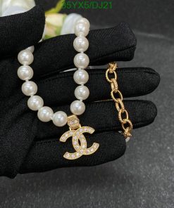 Elegant pearl bracelet and gold pendant on black glove.