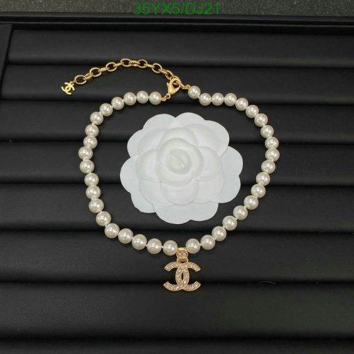 Pearl bracelet with flower and anchor charm on black background.