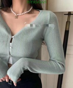 Woman in green cardigan with pearl necklace.