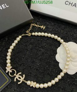 Pearl bracelet with gold charm on black surface.