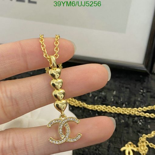 Gold heart chain with sparkly pendant held by fingers.