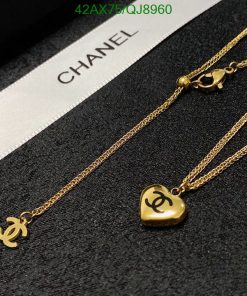 Gold Chanel logo necklaces on dark fabric.