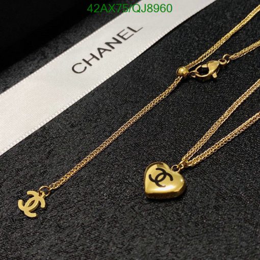 Gold Chanel logo necklaces on dark fabric.