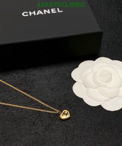 Chanel necklace and box with white flower on black textile.