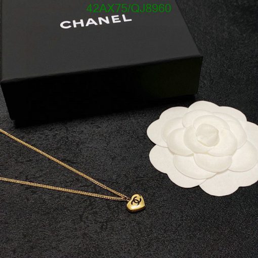 Chanel necklace and box with white flower on black textile.