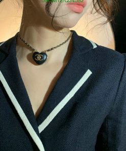 Woman wearing necklace with heart-shaped pendant.