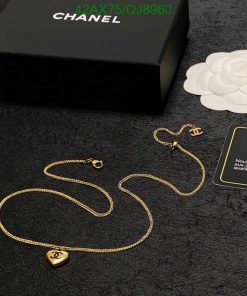 Gold necklace with pendant on black surface near box.