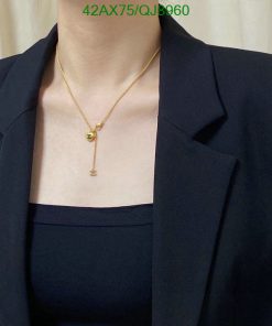 Woman wearing gold pendant necklace with black blazer.