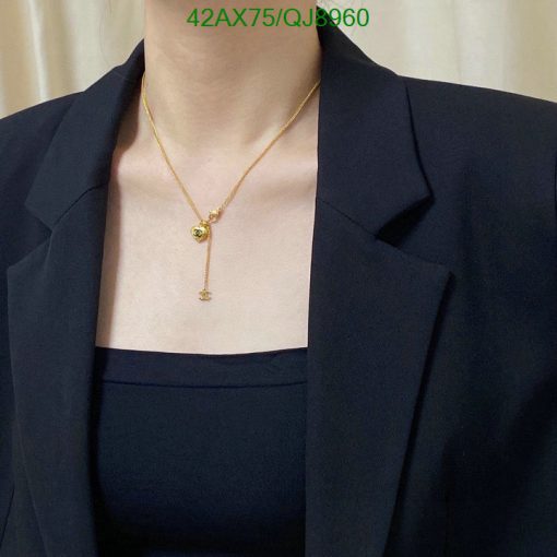 Woman wearing gold pendant necklace with black blazer.