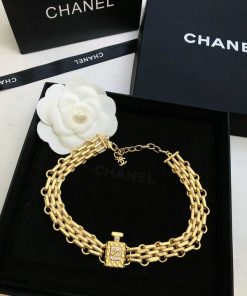 Gold chain bracelet on designer packaging with white flower