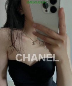 Person taking selfie with smartphone, black top, necklace visible.