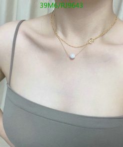 Person wearing necklace with pearl pendant.