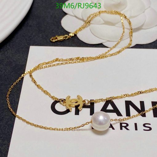 Gold necklace with pearl pendant on branded card.