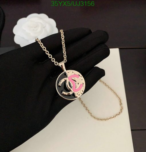 Elegant circular pendant necklace on black glove.