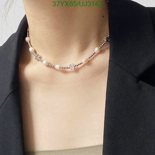 Woman wearing pearl choker necklace with black outfit.