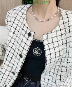 Woman wearing stylish tweed jacket and pearl necklace.