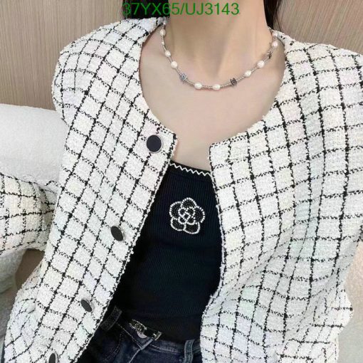 Woman wearing stylish tweed jacket and pearl necklace.