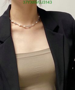 Woman with necklace wearing a blazer and top.