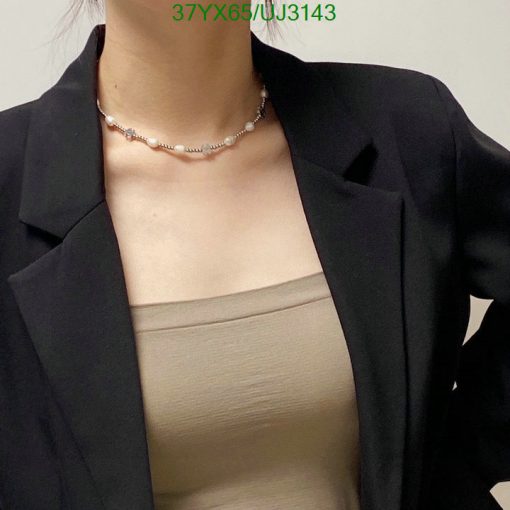 Woman with necklace wearing a blazer and top.