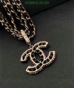 Designer logo pendant with pink gemstones on black background.