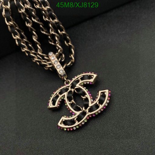 Designer logo pendant with pink gemstones on black background.