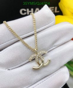 Gold pendant on white glove, yellow flowers background.